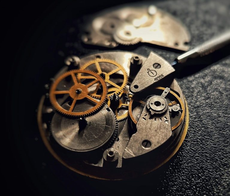 Detailansicht eines mechanischen Uhrwerks mit goldenen Zahnrädern und Metallteilen.
